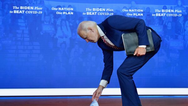 Кандидат в президенты США Джо Байден наклоняется за упавшей медицинской маской - Sputnik Latvija
