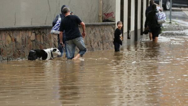 Люди идут по затопленной улице после проливных дождей в Хагене, Германия - Sputnik Латвия