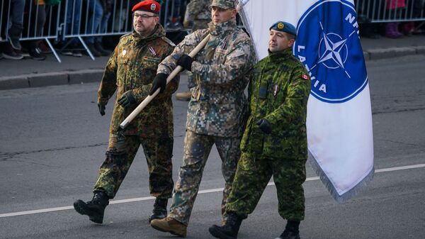 Немецкий, латвийский и канадский военные с флагом Расширенной передовой группы НАТО в Латвии - Sputnik Латвия
