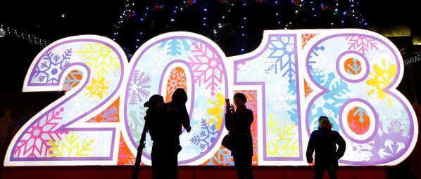 People take photos at a New Year tree installed on Oktyabrskaya Square for the upcoming New Year and Christmas season in Minsk, Belarus - Sputnik Latvija