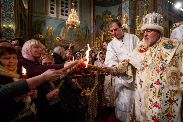 Митрополит Рижский и всея Латвии Александр раздает верующим Благодатный огонь, привезенный из Иерусалима - Sputnik Латвия