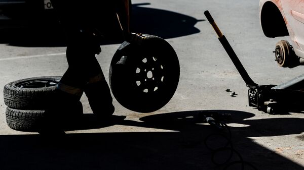 Работник меняет колесо в шиномонтажной мастерской - Sputnik Latvija